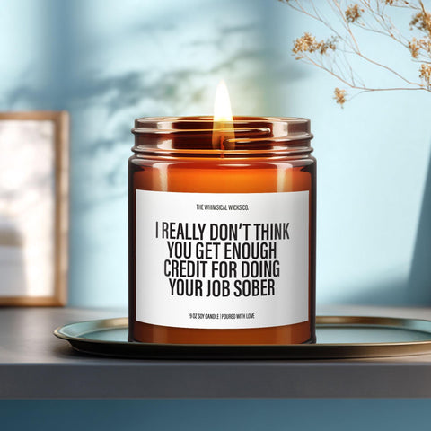 9oz amber glass soy candle with the label βI really donβt think you get enough credit for doing your job sober,β lit and centered on a ceramic tray in a sunlit, minimalist setting. A witty, sarcastic message perfect for coworker gifts or workplace humor decor.