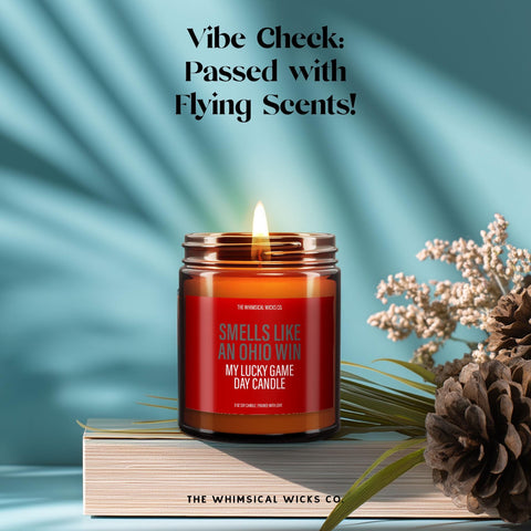“Smells Like an Ohio Win” candle surrounded by flowers and decor, styled for game day vibes. Light humor and sporty charm make it a unique gift. Amber jar glows warmly. Ideal for tailgate lovers and fanatics alike. 100% soy wax, hand-poured with love.