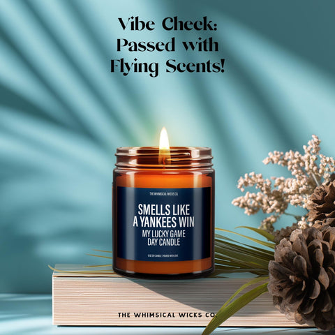 Humorous Yankees fan candle glowing atop a book stack with florals—bold, sporty energy for baseball lovers with taste.
