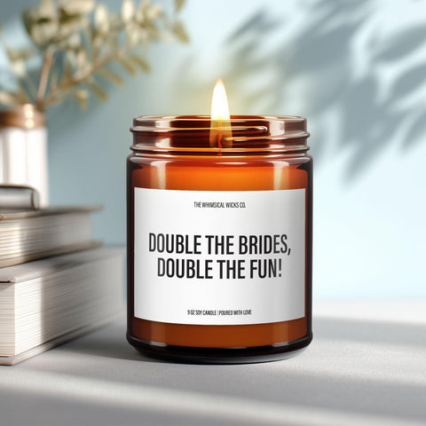 Close-up of a 9oz amber glass jar candle with black metal lid, white label reading “Double the Brides, Double the Fun” in bold black text, styled on a neutral background with warm lighting, perfect for cheeky lesbian wedding or engagement gifting.