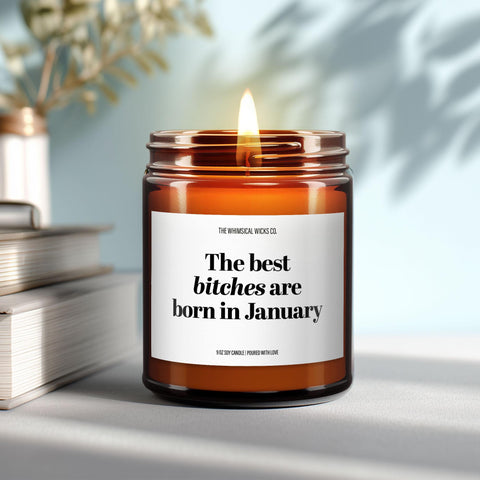 Close-up of a 9oz amber glass jar candle with black metal lid, white label reading “The Best Bitches Are Born in January” in bold black text, styled on a neutral background with warm lighting, perfect for cheeky January birthday gifting.