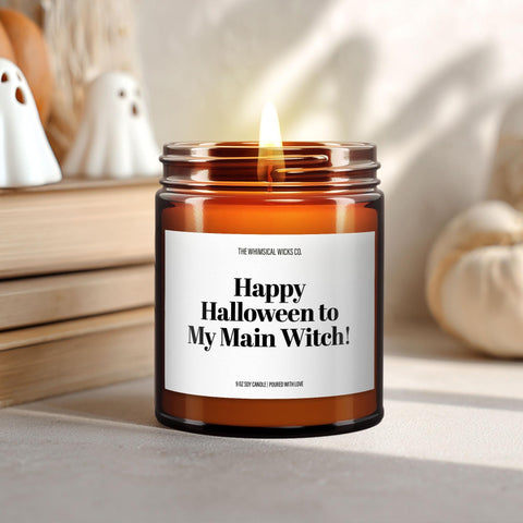Close-up of a 9oz amber glass jar candle with black metal lid, white label reading “Happy Halloween to My Main Witch” in bold black text, styled on a neutral background with warm lighting, perfect for funny witchy Halloween gifting.