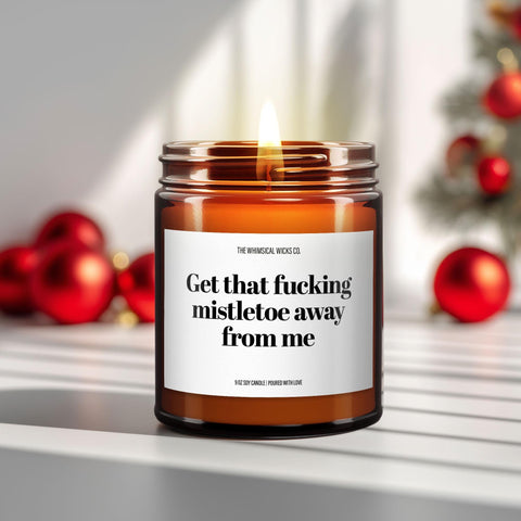 Hero image – 9oz amber glass jar candle
Close-up of a 9oz amber glass jar candle with black metal lid, white label reading “Get That Fucking Mistletoex Away From Me” in bold black text, styled on a neutral background with warm lighting, perfect for sarcastic holiday gifting or anti-romance Christmas decor.
