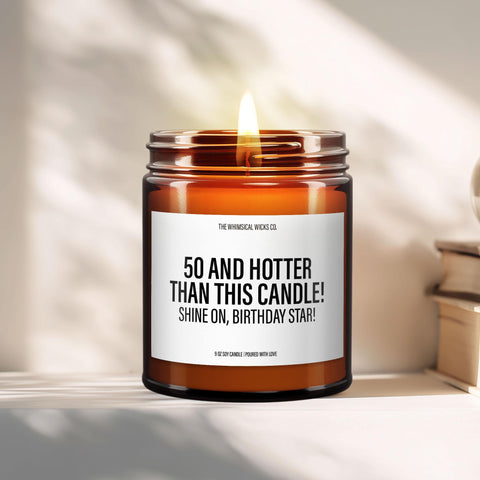 Amber glass candle with bold label that reads “50 and Hotter Than This Candle! Shine On, Birthday Star!” styled on a modern tabletop with soft natural lighting. A humorous milestone birthday gift for women turning 50.