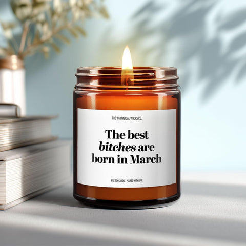 Close-up of a 9oz amber glass jar candle with black metal lid, white label reading “The Best Bitches Are Born in March” in bold black text, styled on a neutral background with warm lighting, perfect for cheeky March birthday gifting.